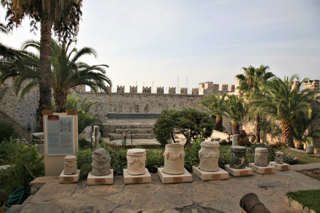 Фрагменты древних колон на фоне крепостной стены.